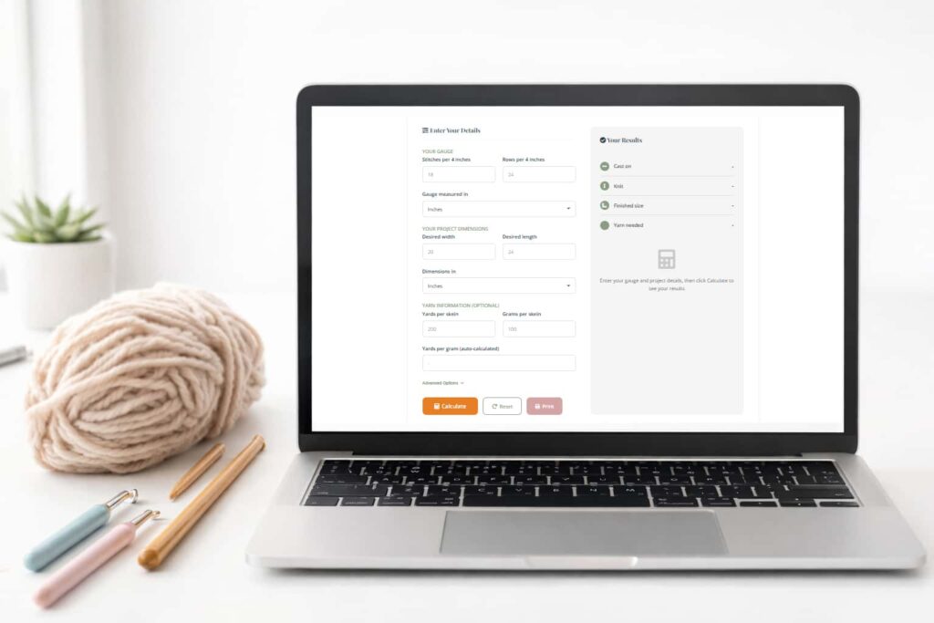 Laptop showing a knitting gauge calculator tool on screen surrounded by yarn and knitting supplies